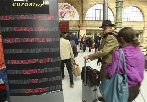People queue at the Eurostar train check in desk while an information board reads "All Eurostar trains fully booked Friday and Saturday" at the Gare du Nord train station in Paris, April 16. 